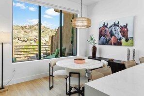 A dining area with a round table, chairs, and a hanging light fixture.