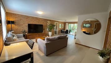 A modern living room with a sofa, a dining table, and a TV.