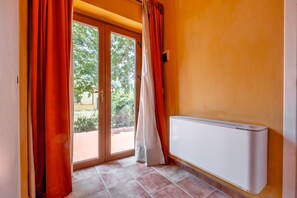 Una habitación con puerta de vidrio corredera, un radiador y suelo de baldosas.