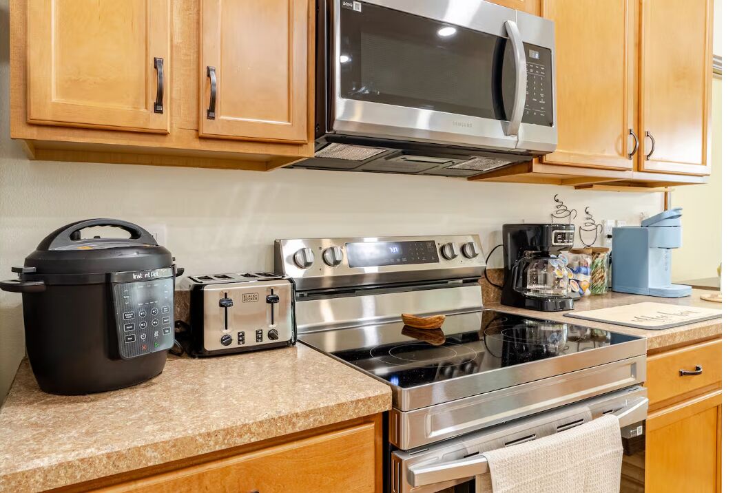 A modern kitchen with stainless steel appliances, wooden cabinets, and a granite countertop.
