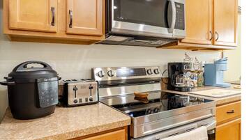 A modern kitchen with stainless steel appliances, wooden cabinets, and a granite countertop.