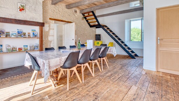 Een rustieke eethoek met een houten tafel, stoelen en een boekenplank vol boeken.