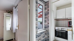 Une cuisine avec un mur en briques, des meubles blancs et une fenêtre.