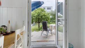 A room with a sliding glass door leading to a patio with a chair, a table, and a blue umbrella. - Apartment 'Rotes Haus' with Mountain View, Private Terrace and Wi-Fi (Konstanz)