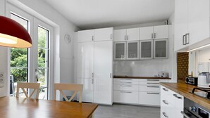 A modern kitchen with white cabinets, a wooden table, and a red pendant light. - Apartment 'Rotes Haus' with Mountain View, Private Terrace and Wi-Fi (Konstanz)
