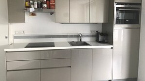 A kitchen with a built-in oven, a sink, and a wine rack with bottles. - Apartment 'Bechtel' with Balcony and Wi-Fi (Langenargen)