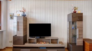 Un salon moderne doté d’un téléviseur à écran plat, de meubles en bois et d’objets décoratifs.