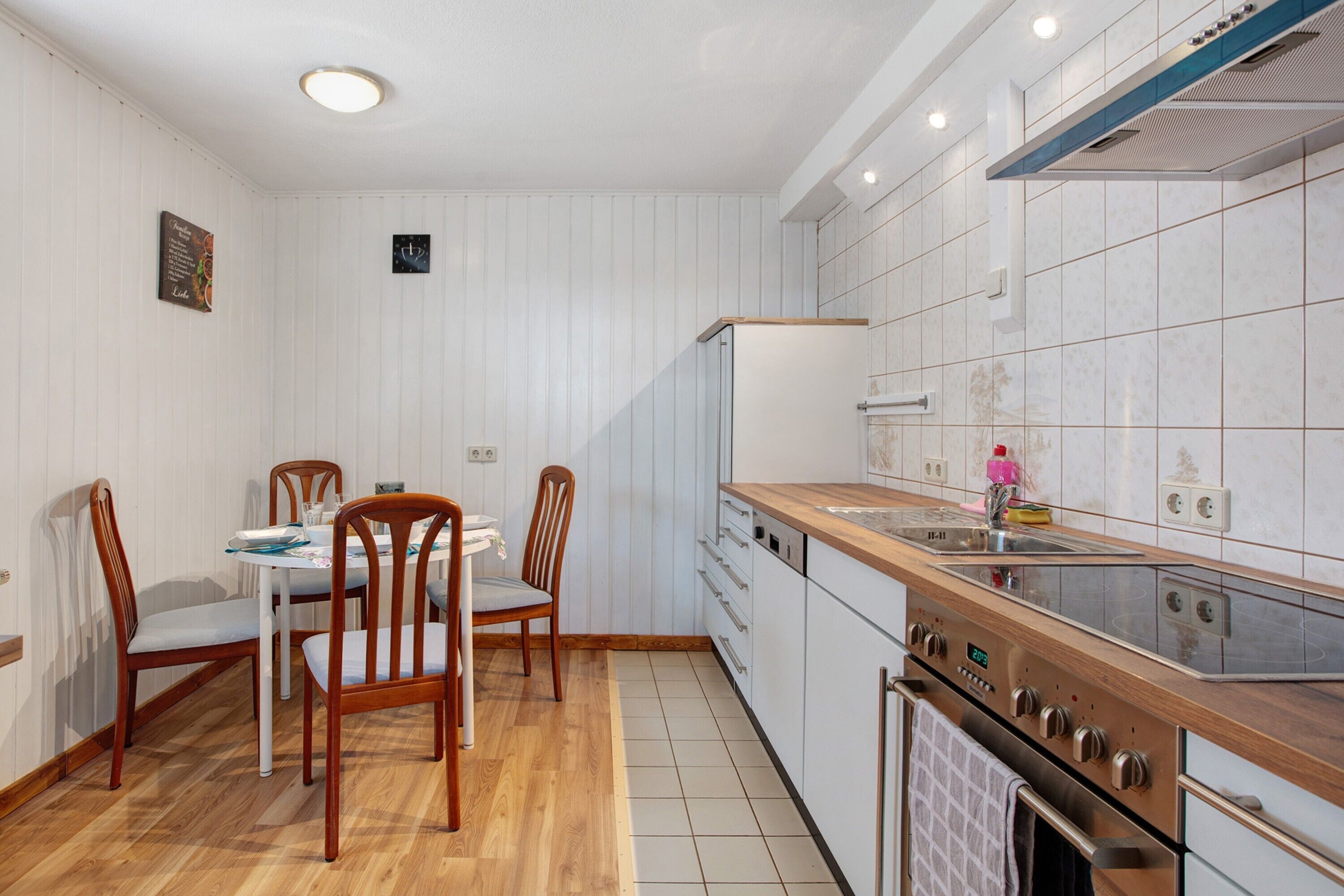 A kitchen with wooden cabinets, a built-in oven, and a dining area with chairs and a table.