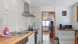 Une cuisine équipée d’un évier en acier inoxydable, d’un four à micro-ondes et d’un plan de travail en bois.