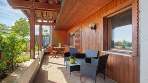 Une terrasse extérieure avec des meubles en bois, une table et des chaises.