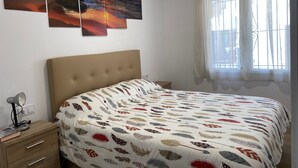 A bedroom with a bed, a nightstand, a lamp, and a window with curtains. - Apartment 'Muscletes' with Mountain View, Wi-Fi and Air Conditioning (L'Escala)