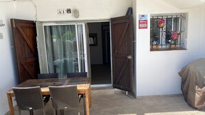 An outdoor patio with a wooden table and chairs, a sliding glass door, and a covered area. - Apartment 'Muscletes' with Mountain View, Wi-Fi and Air Conditioning (L'Escala)