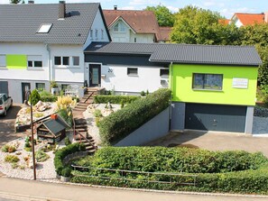 Un edificio residencial con detalles verdes, el número '20' visible en la fachada y un pequeño espacio al aire libre con mesa y sillas.