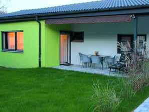 A green building with a patio area, a table with chairs, and a small garden. - Dieterich 1 Apartment with Terrace, Private Garden and Wi-Fi (Beuren)