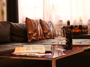 Una sala de estar moderna con un sofá, una mesa de centro con documentos, dos copas de vino y una botella.