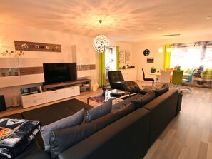 Ein modernes Wohnzimmer mit einer Couch, einem Fernseher und einer Deckenleuchte.