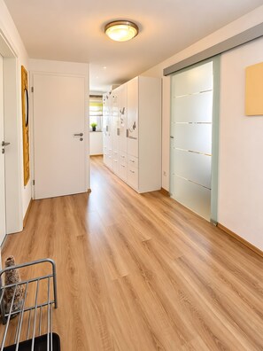A hallway with wooden flooring, a metal chair, and a door with a circular light fixture. - 5-Sterne-Ferienwohnung 'Dieterich 2' mit 2 Schlafzimmern und 27 m² großem Balkon (Beuren)