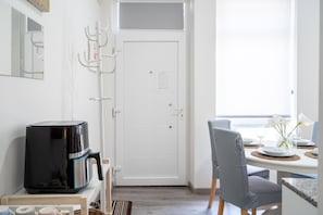 A modern kitchen with a coffee maker, a white door, and a dining table set for two.