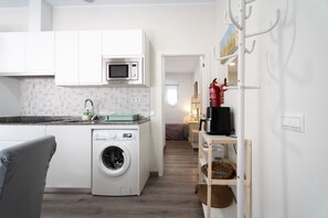 A compact kitchen with a washing machine, microwave, and a coffee machine.