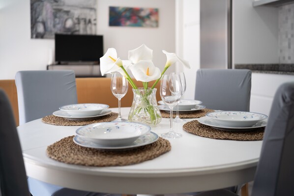 A dining table set with plates, glasses, and a vase with flowers.
