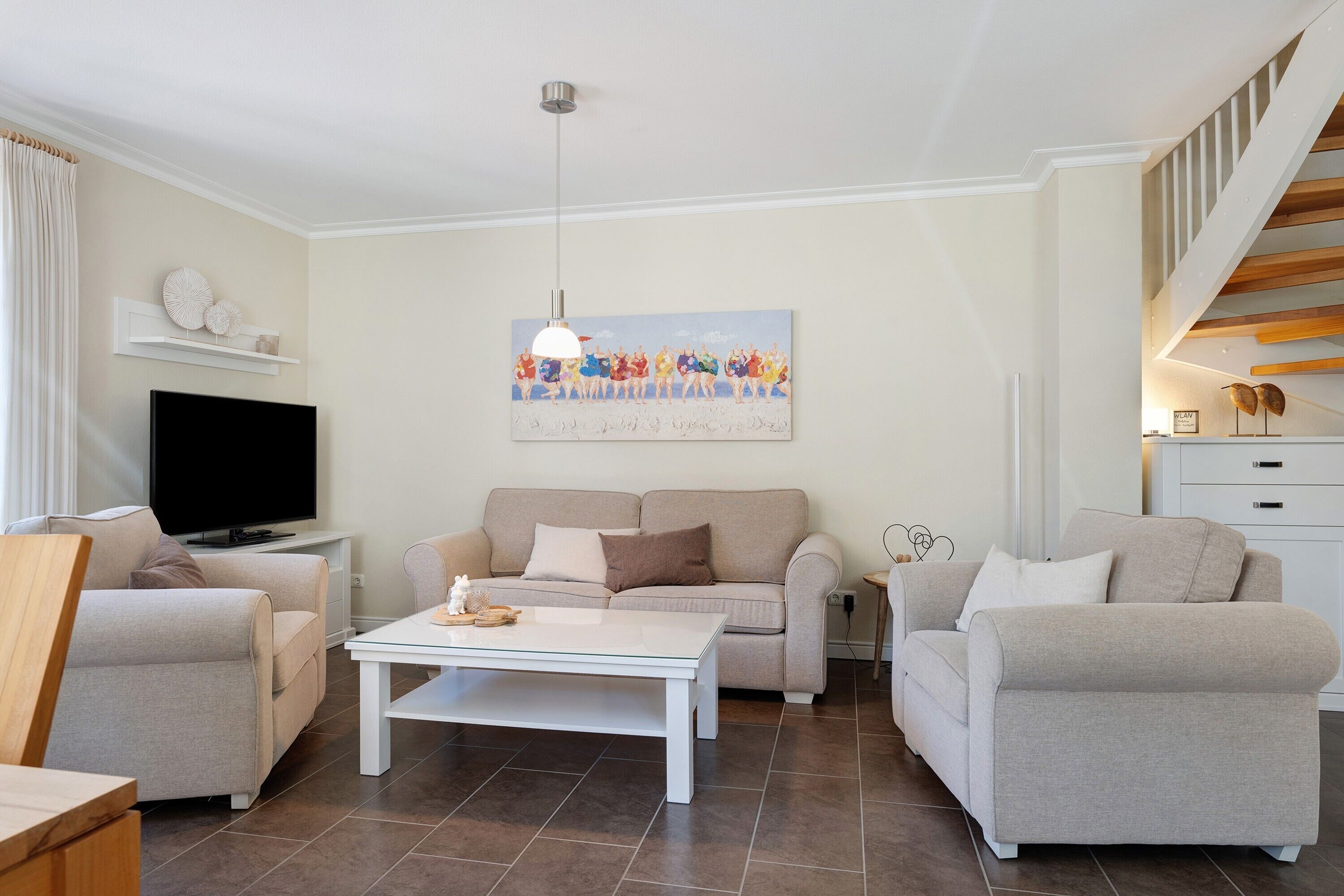A living room with a sofa, a coffee table, a TV, and a painting on the wall.