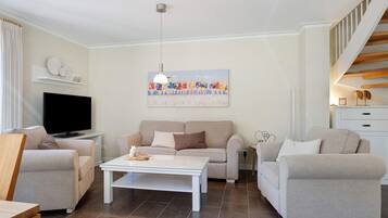 A living room with a sofa, a coffee table, a TV, and a painting on the wall.