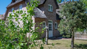 A house with a thatched roof, a brick exterior, and a white door. - Holiday Home 'Huus Alex' with Private Terrace, Private Garden and Wi-Fi (St. Peter-Ording Dorf)