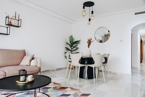 A modern living room with a sofa, coffee table, dining table, chairs, a potted plant, and a mirror. - Apartment 'Calpe Bay' with Shared Pool, Wi-Fi and Air Conditioning (Calp)
