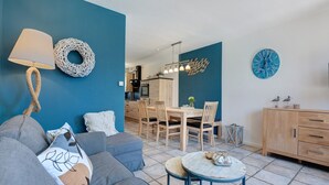 A modern living room with a sofa, a round coffee table, and a dining area with wooden chairs and a table. - Düün Drööm – Your Dream House Behind the Dunes (St. Peter-Ording Dorf)