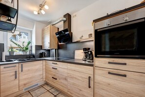 A modern kitchen with wooden cabinets, a built-in oven, and a coffee maker.