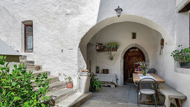 A rustic courtyard with a wooden table and bench, a potted plant, and a stone staircase. - Apartment 'Gravetsch Kloster Säben' with Mountain View, Shared Garden and Wi-Fi (Villandro)