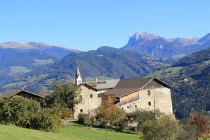 Un village rural avec des bâtiments en pierre, une église et des montagnes en arrière-plan.