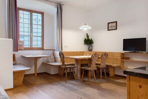 A cozy room with a wooden table, two chairs, a bench, a TV, and a window with curtains. - Apartment 'Gravetsch Kloster Säben' with Mountain View, Shared Garden and Wi-Fi (Villandro)