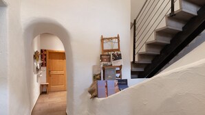 A hallway with a wooden door, a small stool, and books on a shelf. - Apartment 'Gravetsch Kloster Säben' with Mountain View, Shared Garden and Wi-Fi (Villandro)