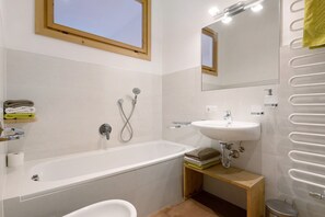 Une salle de bain moderne équipée d’une baignoire, d’un lavabo, d’un miroir et d’un porte-serviettes.