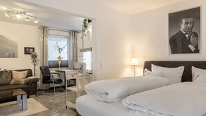 A hotel room with a bed, a desk, a chair, a couch, and a window with curtains. - Studio 'Moonraker' with Shared Terrace and Wi-Fi (Breisach am Rhein)