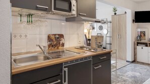 A modern kitchen with a microwave, double sink, and wooden countertop. - Studio 'Moonraker' with Shared Terrace and Wi-Fi (Breisach am Rhein)