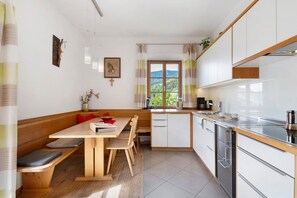 Eine moderne Küche mit einer Holzbank, weißen Schränken und Blick ins Grüne.