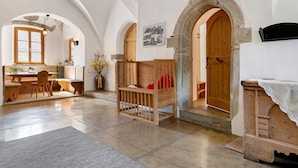 A room with a wooden crib, a wooden bench, and a stone archway. - Apartment 'Gravetsch' with Mountain View, Shared Garden and Wi-Fi (Villandro)