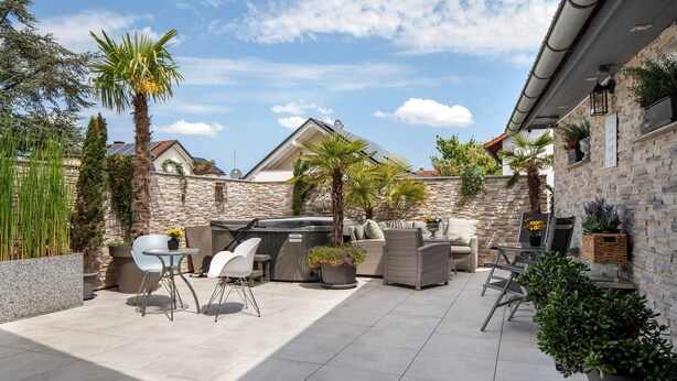 Eine Terrasse im Freien mit Steinmauern, einem Grill und Sitzgelegenheiten.