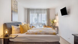 Ein modernes Hotelzimmer mit einem Bett, Nachttischen, einem Flachbildfernseher und einem Fenster mit Vorhängen.