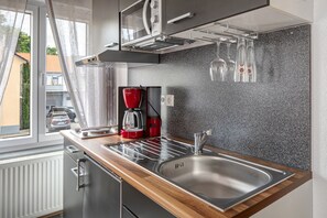 A modern kitchen with a stainless steel sink, wooden countertop, and a built-in range hood. - Studio 'Fernando' with Shared Terrace and Wi-Fi (Breisach am Rhein)