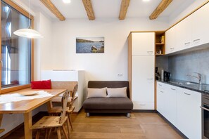 A compact kitchen with a dining area, a sofa, and a window with a view of a body of water. - Apartment 'Schloss Gravetsch Castel' with Mountain View and Shared Garden (Villandro)