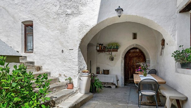 A rustic courtyard with a wooden table and bench, a potted plant, and a stone staircase. - Apartment 'Schloss Gravetsch Castel' with Mountain View and Shared Garden (Villandro)