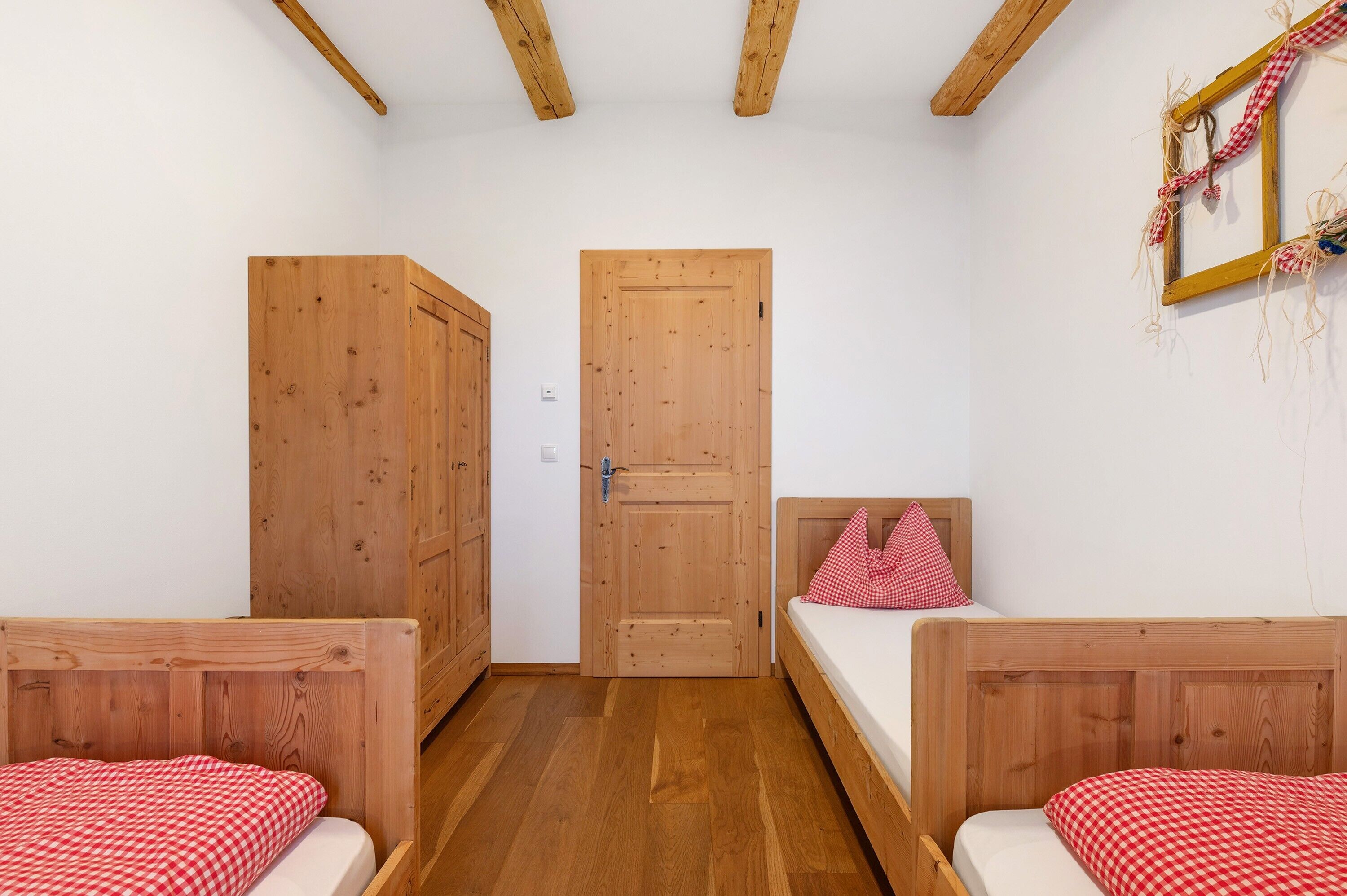 Une pièce avec deux lits en bois, une armoire en bois et une porte en bois.