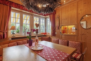 A dining area with a wooden table, benches, and a window with curtains. - Apartment 'Deluxe' with Mountain View, Private Terrace and Wi-Fi (Höchenschwand)