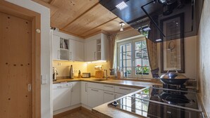 A kitchen with white cabinets, a stove, and a window with curtains.
