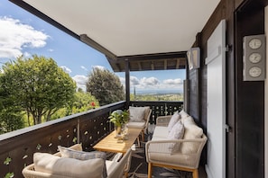 A balcony with outdoor furniture, a table with a vase, and a view of trees and mountains. - Apartment 'Deluxe' with Mountain View, Private Terrace and Wi-Fi (Höchenschwand)