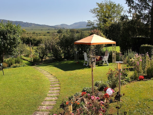 A garden with a patio, a stone pathway, and a view of the hills.