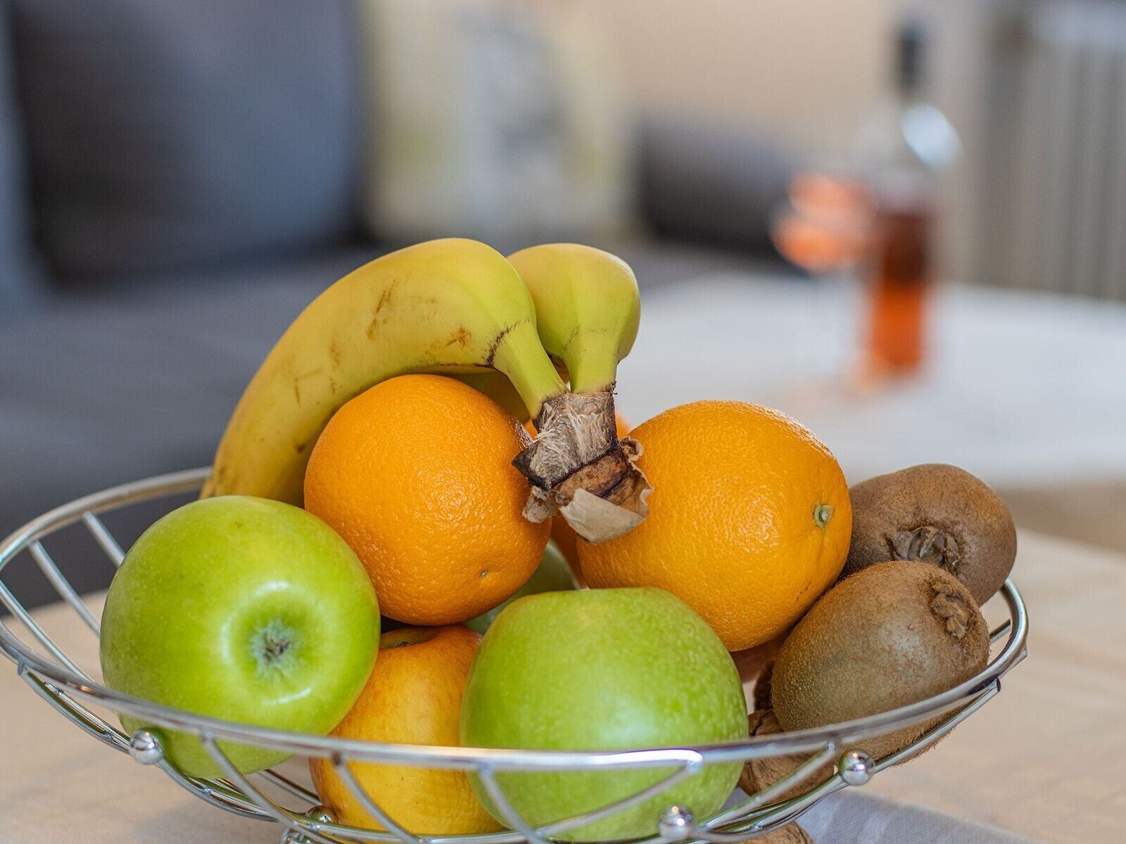 A fruit basket containing bananas, oranges, apples, and kiwis.